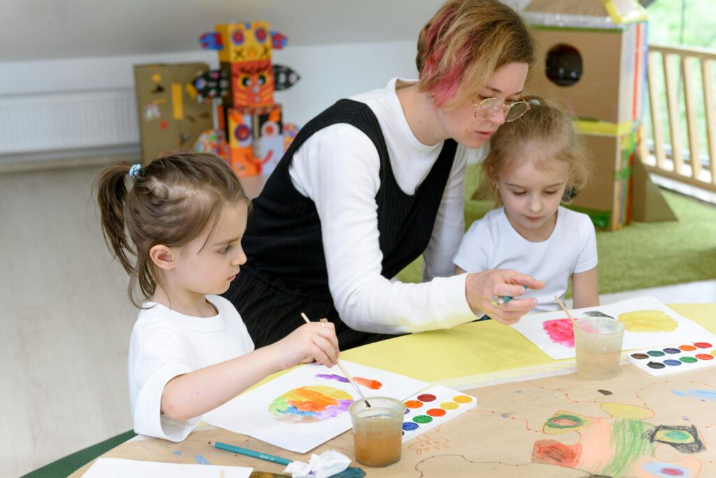 Teacher guides children in a watercolor painting session at school, embracing creativity.